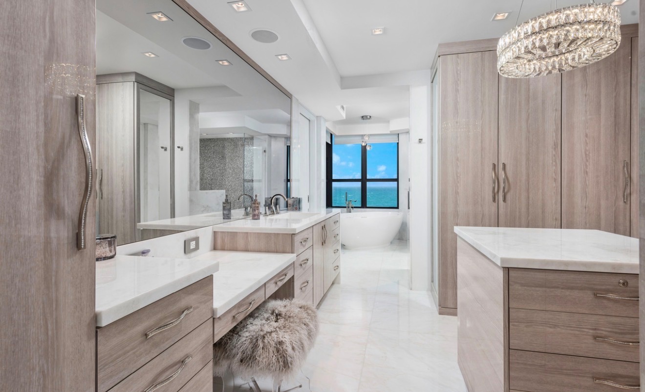 Custom dressing room with pale wood cabinetry and crystal lighting