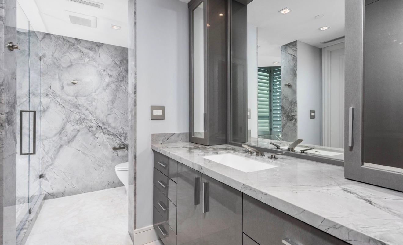 Custom gray vanity with a marble countertop and full-height mirrors