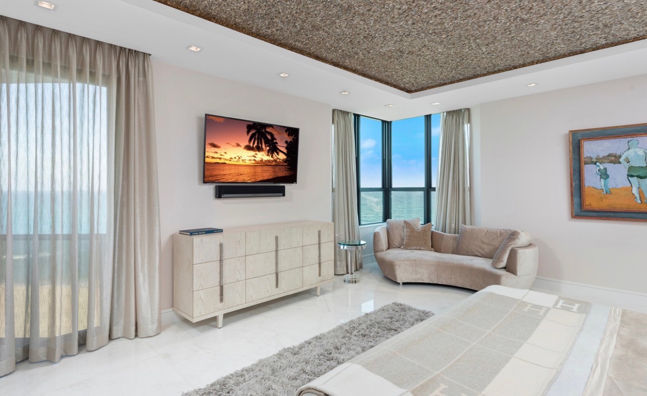 Serene oceanfront bedroom with custom cabinetry and a curved lounge sofa